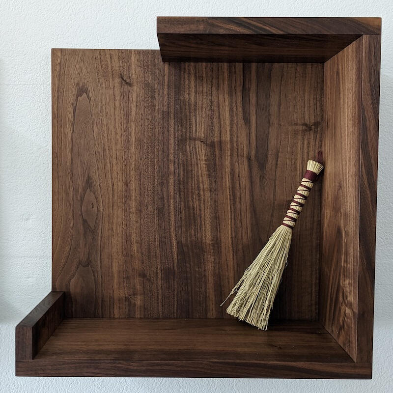 walnut floating wall shelf with small broom